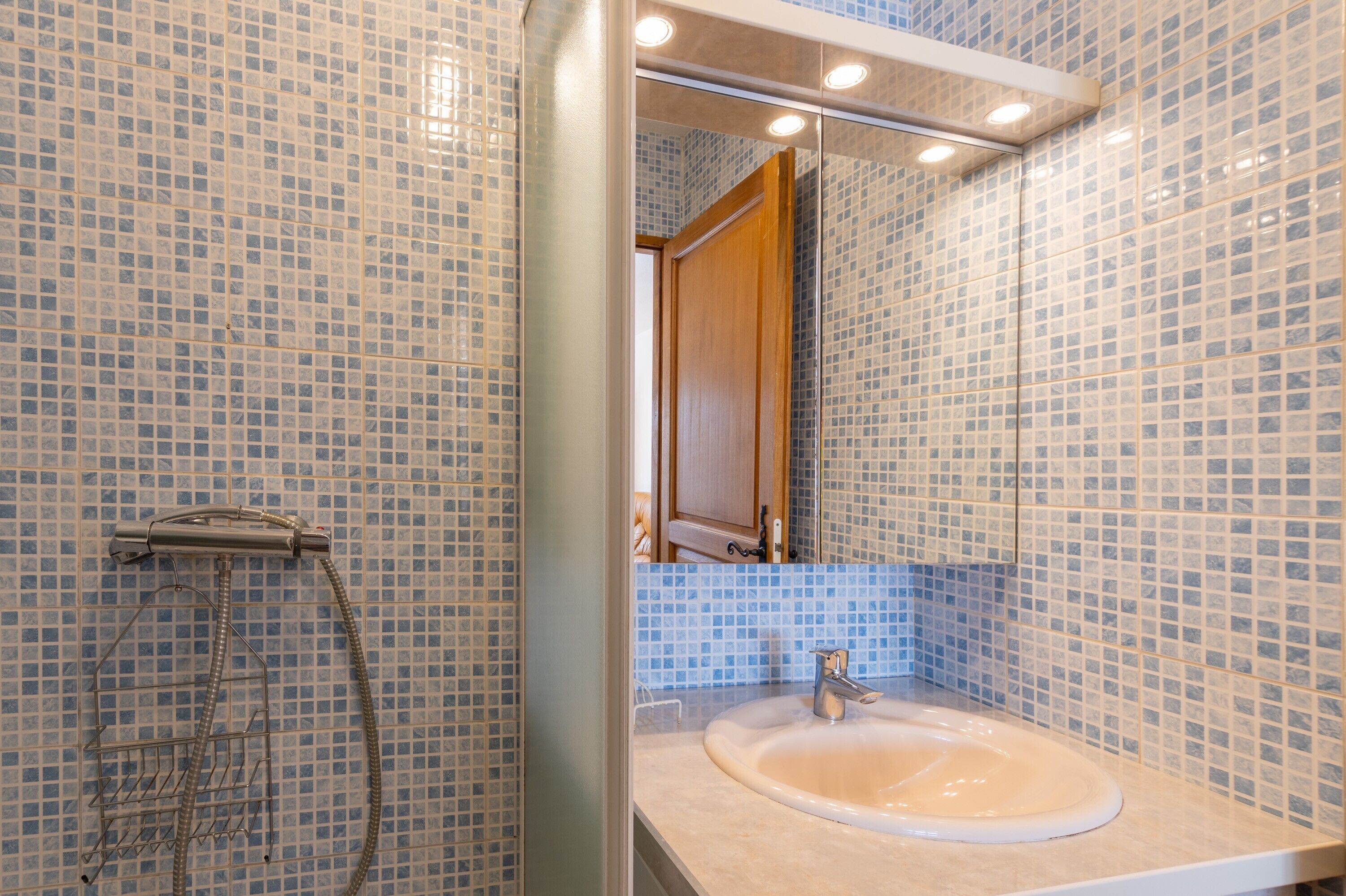 Ein Badezimmer mit Waschbecken, Spiegel, Dusche und Fliesen.