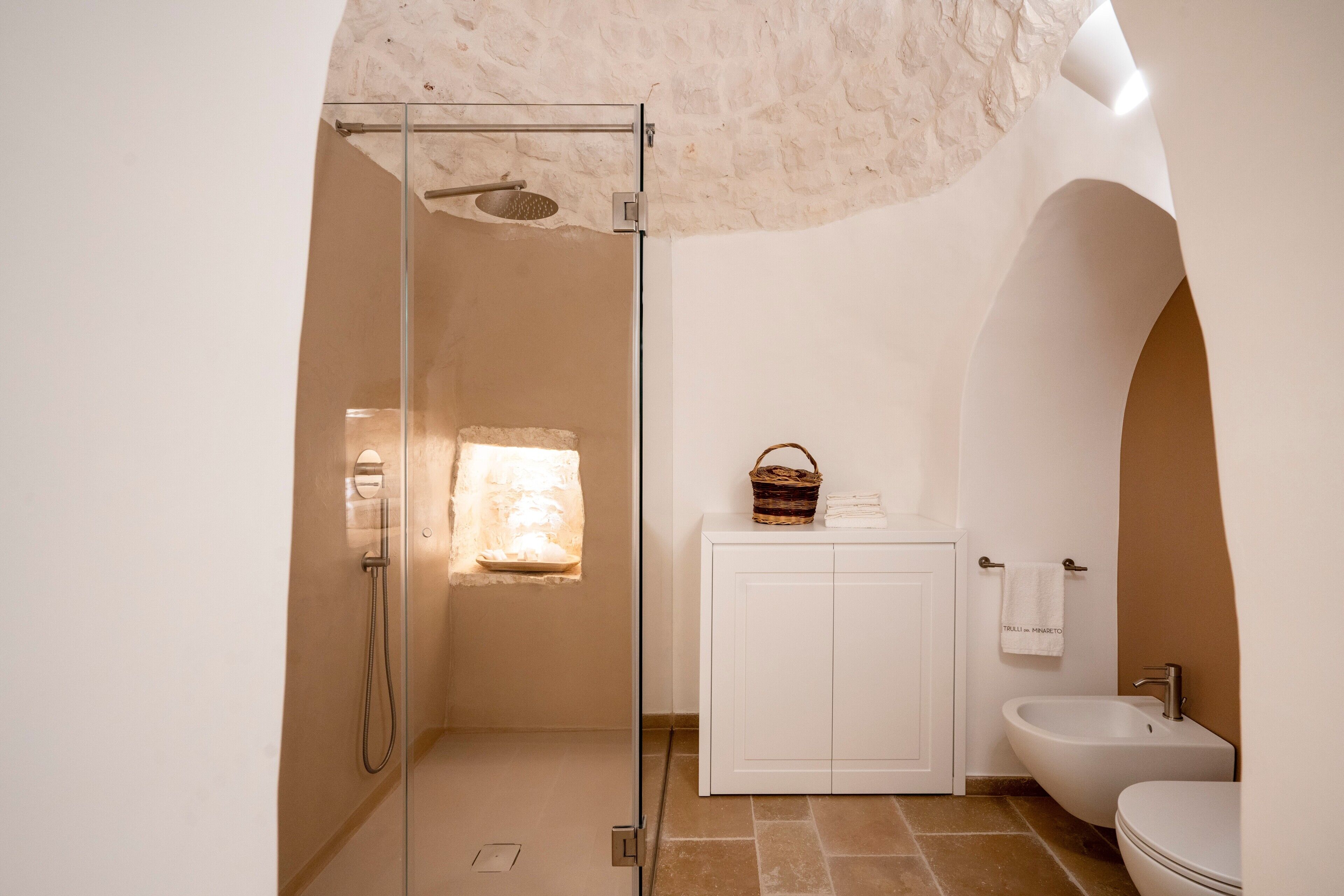 Une salle de bain avec une douche à parois de verre, un lavabo blanc et un meuble blanc.