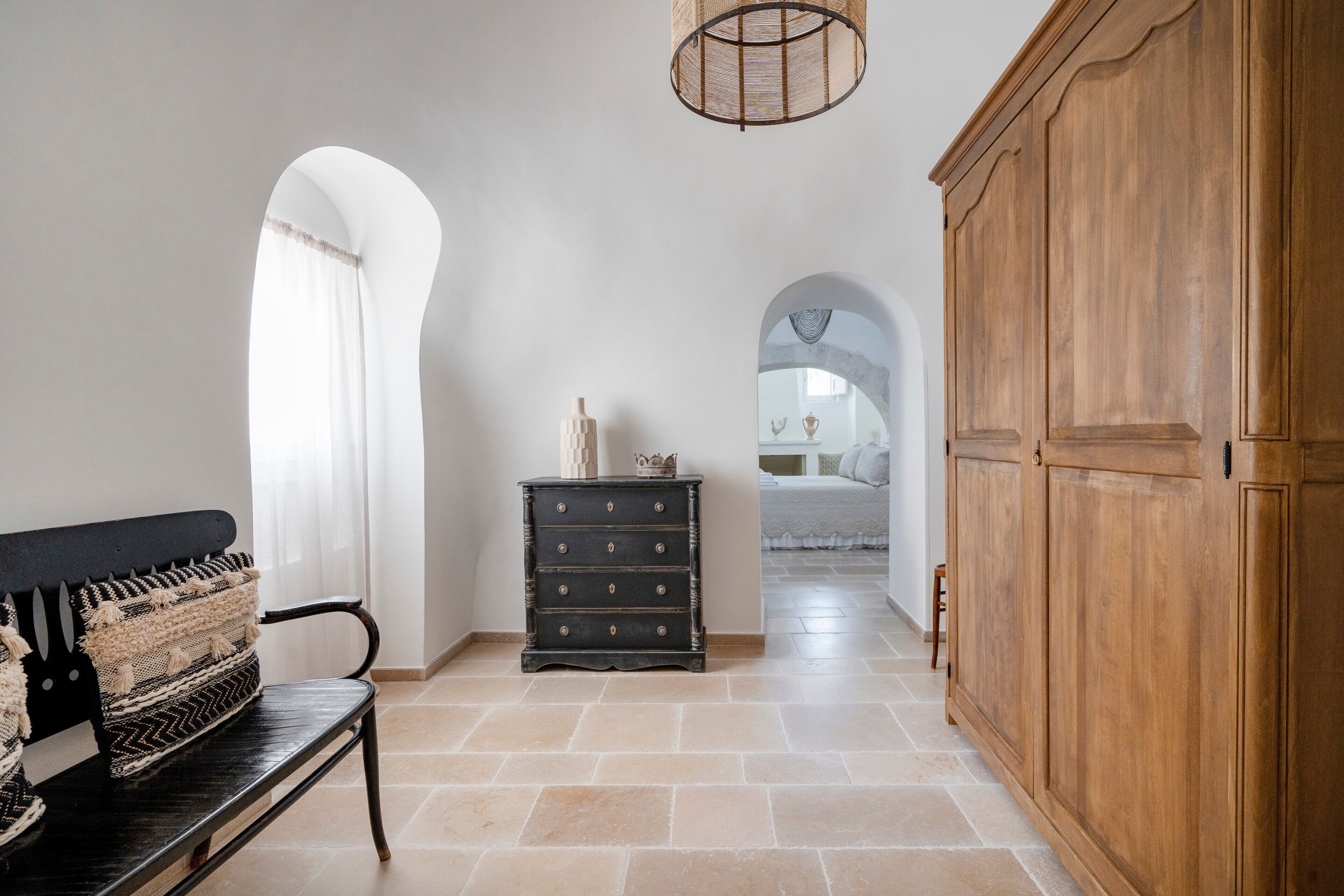 Un couloir avec un banc, une armoire en bois et une commode.