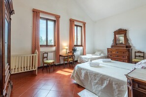 Une chambre avec deux lits, un bureau, une chaise, une commode et une fenêtre avec des rideaux.