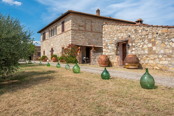A stone building with a tiled roof, a door, and large terracotta pots in the yard.