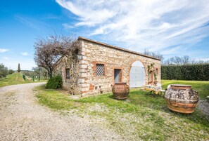 A stone building with a gravel path, two large pots, and a door. - Holiday Home "Limonaia" with Shared Pool, Communal Garden and Wi-Fi (Castelnuovo Berardenga)