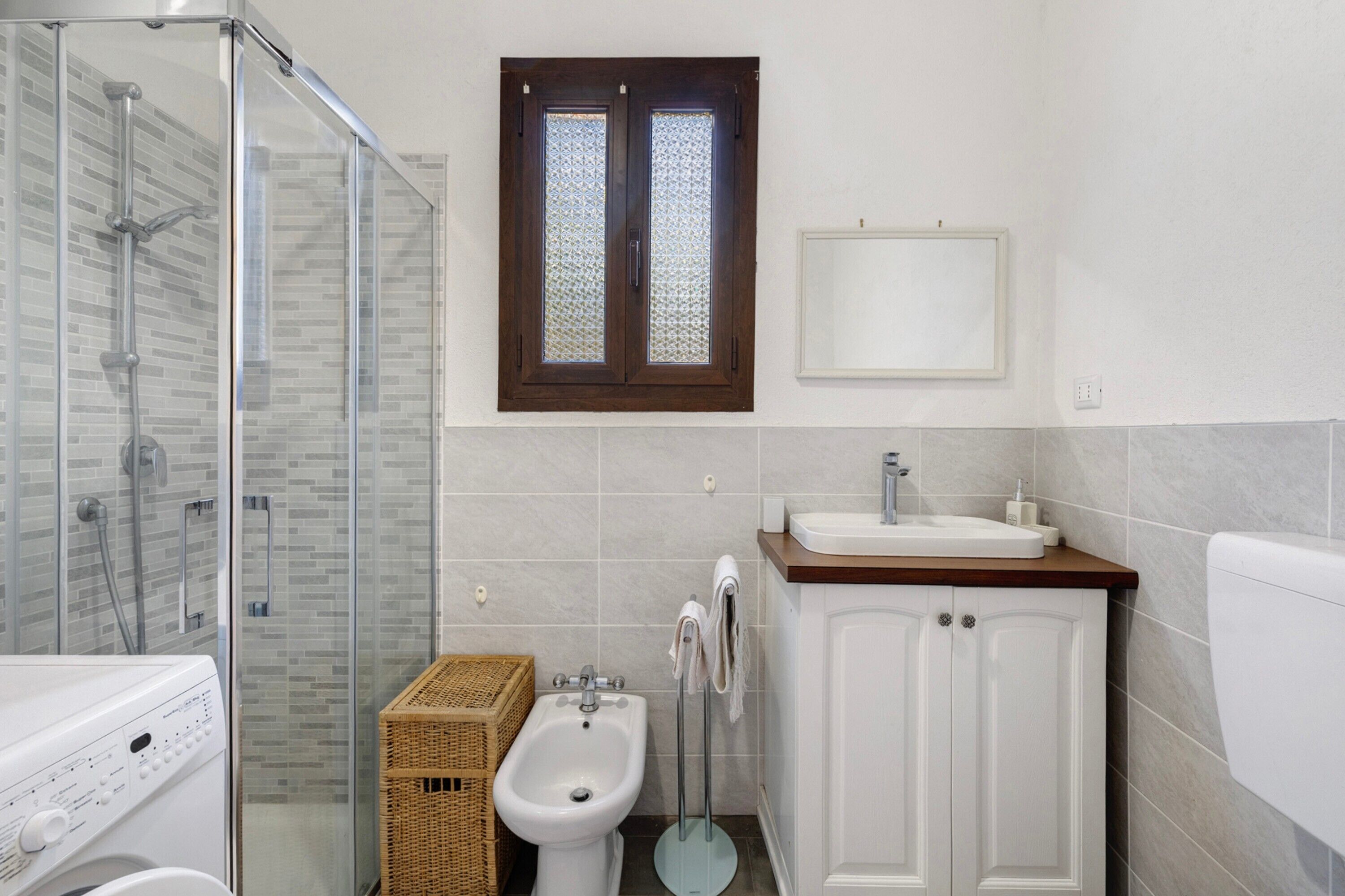 Ein Badezimmer mit Duschkabine aus Glas, einem Bidet, einem Waschbecken und einer Toilette.
