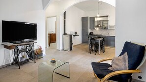 Una sala de estar con televisor, una mesa de centro de vidrio y un sillón azul.