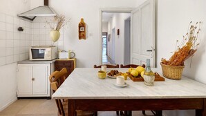 Una cocina con una mesa de comedor, sillas, un microondas, un armario y una cesta de plantas secas.