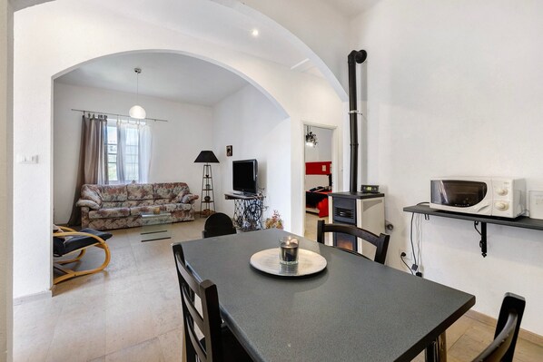A living room with a sofa, a dining table with chairs, a TV, and a microwave.