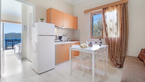 A compact kitchen with a white refrigerator, orange cabinets, and a dining area with a table and chairs.