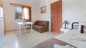 A room with a bed, a sofa, a table, and a window.