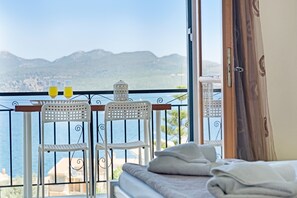 A balcony with two white chairs, a table, and two glasses of orange juice. - Apartment 'With Sea View M4' with Sea View, Wi-Fi and Air Conditioning (Nikiana)