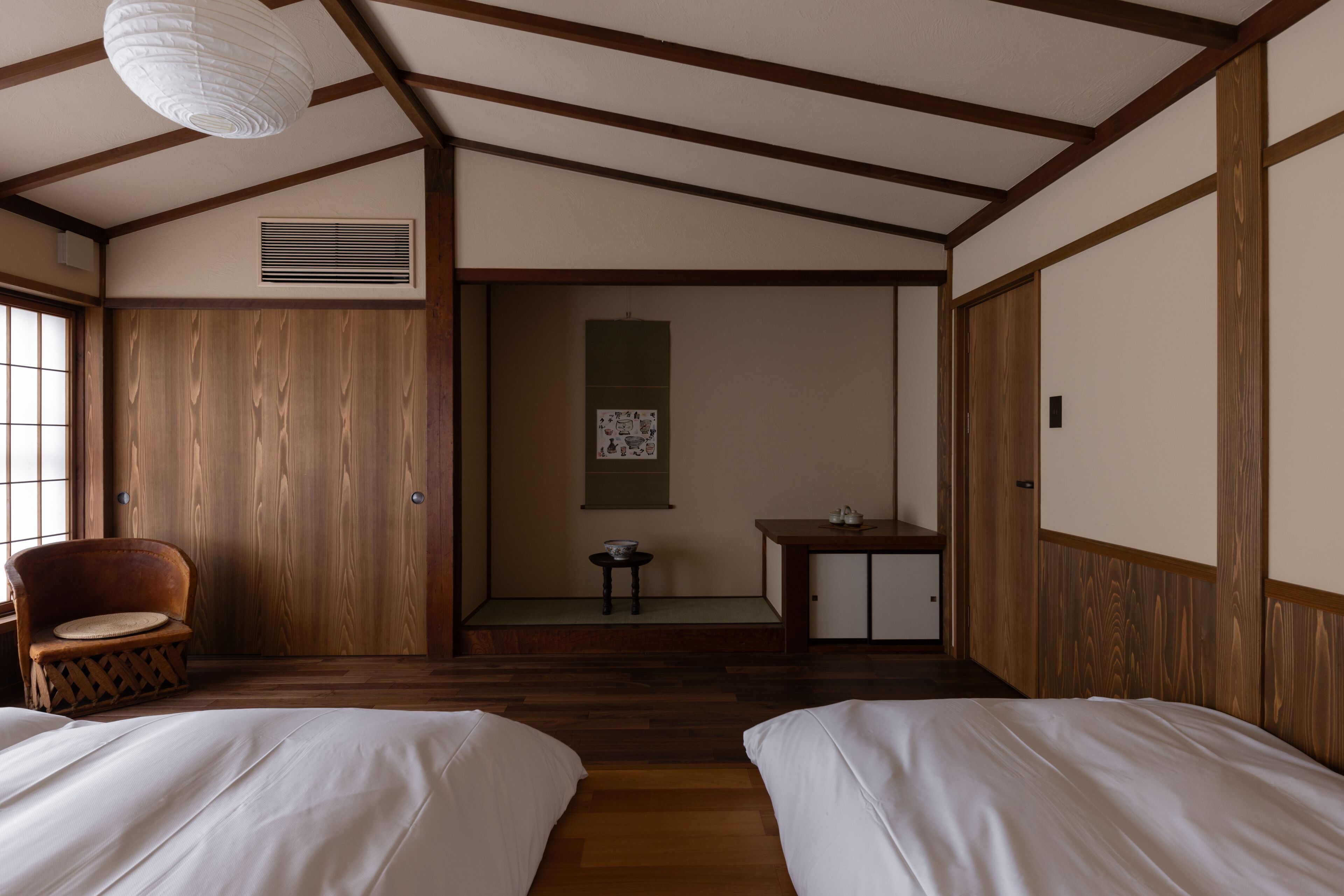 Una habitación tradicional japonesa con vigas de madera, suelo de tatami y dos camas.