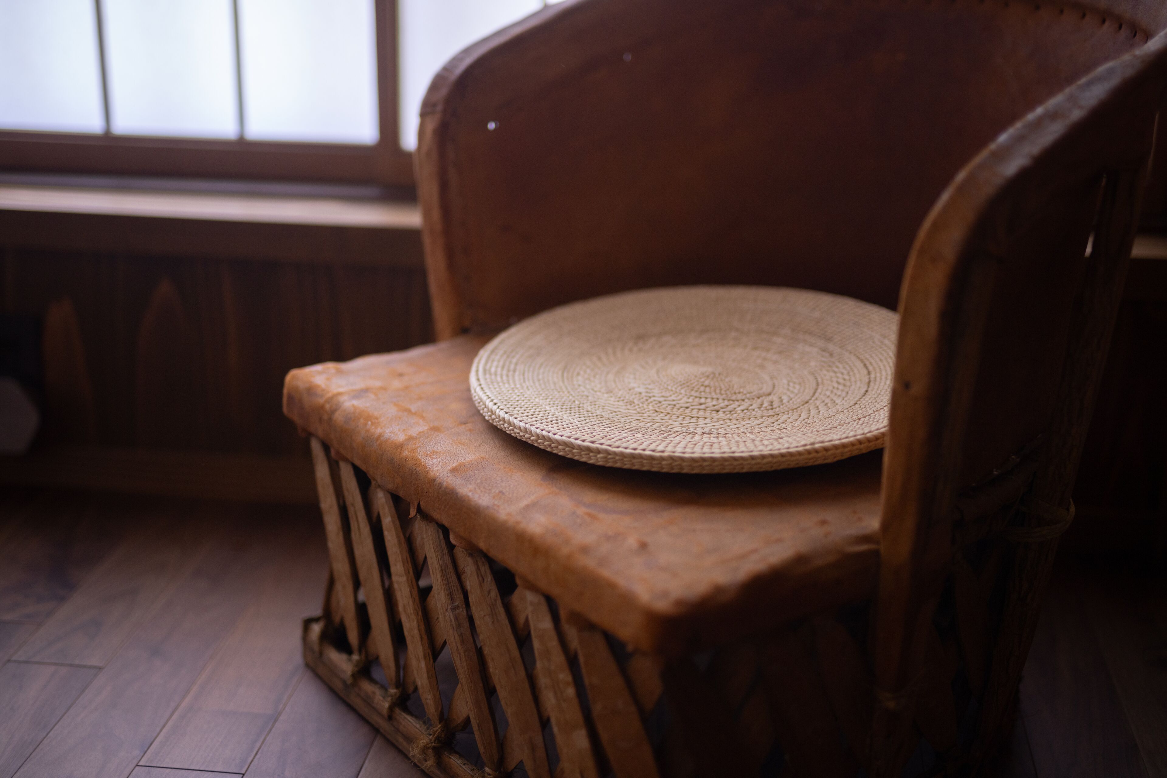 Un banco de madera con cojín de asiento tejido.