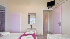 A hotel room with two beds, a television, a mirror, a small table with a vase, and a view of the outdoors. - Apartment 'Standard  with Sea View 2' with Sea View, Wi-Fi and Air Conditioning (Nikiana)