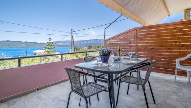 A terrace with a table set for dining, overlooking a body of water and mountains. - Apartment 'Standard  with Sea View 2' with Sea View, Wi-Fi and Air Conditioning (Nikiana)