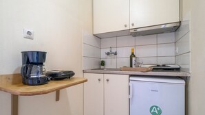 A compact kitchen with a coffee maker, a small refrigerator, and a sink. - Apartment 'Standard  with Sea View 2' with Sea View, Wi-Fi and Air Conditioning (Nikiana)