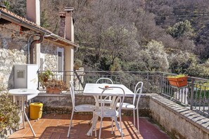 A terrace with a table and chairs, a potted plant, and a view of a hillside. - Apartment 'La Dimora Del Tempo Perduto' with Mountain View, Shared Terrace and Wi-Fi (Castelvecchio di Rocca Barbena)