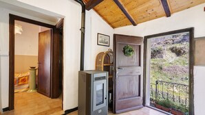 Une pièce avec un plafond en bois, une porte ornée d’une guirlande, un radiateur et une vue sur un jardin.