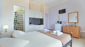 A bedroom with a bed, a bedside table with a lamp, a bathroom with a shower curtain, a kitchenette, a TV, and a cabinet. - Studio Apartment 'Standard with Sea View 6' with Sea View, Wi-Fi and Air Conditioning (Nikiana)