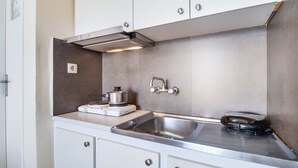 A compact kitchen with a stainless steel sink, a built-in stove, and a range hood. - Studio Apartment 'Standard with Sea View 6' with Sea View, Wi-Fi and Air Conditioning (Nikiana)