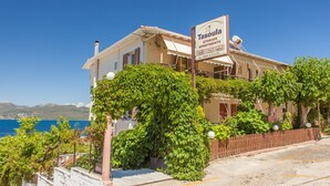 A building with a sign for 'Tasoulia Studios Apartments' featuring a view of the sea.