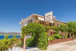 A building with a sign for 'Tasoulia Studios Apartments' featuring a view of the sea.