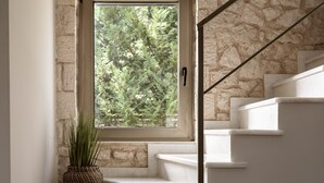 A staircase with a stone wall, a window with a view of trees, and a potted plant. - Villa 'Avesta Private Villas - Kallisto' with Sea View, Private Pool and Air Conditioning (Lefkada)