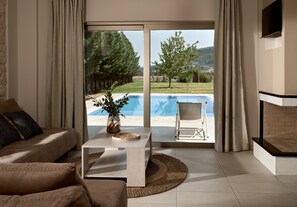 A living room with a sofa, coffee table, and a view of a swimming pool and outdoor area.