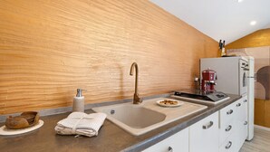 A modern kitchen with a wooden wall, a sink, a coffee machine, and a refrigerator. - Apartment 'La Terrazza Del Tempo' with Mountain View, Wi-Fi and Air Conditioning (Castelvecchio di Rocca Barbena)