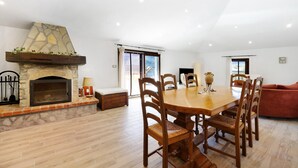 A dining area with a stone fireplace, wooden chairs, a wooden table, and a red sofa. - Apartment 'La Terrazza Del Tempo' with Mountain View, Wi-Fi and Air Conditioning (Castelvecchio di Rocca Barbena)