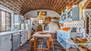 Une cuisine avec un plafond en briques, un sol en pierre et des armoires bleues.
