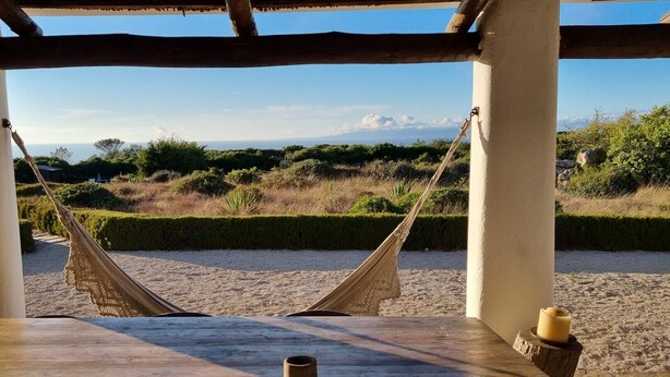 Un hamac suspendu sous une structure en bois, offrant une vue sur un paysage naturel.