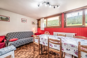 Ein Essbereich mit Tisch, Stühlen, einer Couch und einem Fenster mit Blick auf Grünflächen.