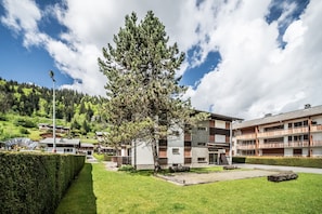 Ein Gebäude mit einem großen Baum davor, einem gepflegten Rasen und blauem Himmel.