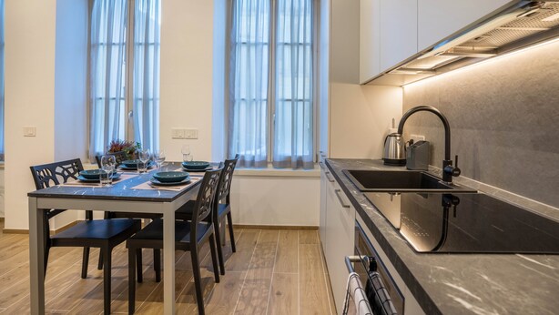 Una cocina moderna con estufa integrada, un lavamanos y un ventanal con cortinas.