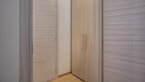 Un pasillo con dos puertas de madera, una cerrada y otra abierta, que dan a una habitación.