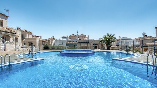 A swimming pool with a circular hot tub, surrounded by a fence, with buildings in the background. - Villa "Solaris" with Shared Pool & Wi-Fi (Torrevieja)