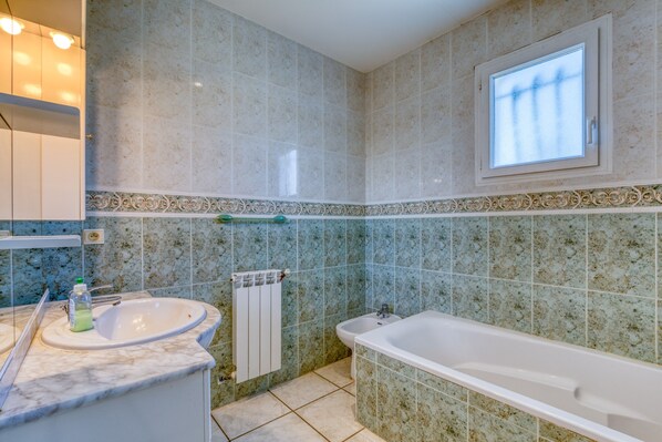Ein Badezimmer mit Waschbecken, Spiegel, Fenster und Badewanne.