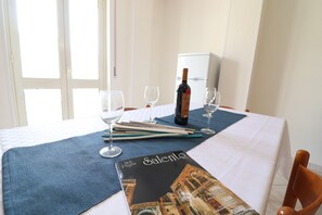 A hotel room with a dining table set with wine glasses, chopsticks, and a magazine.