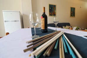 A table with a bottle of wine, two glasses, and a set of chopsticks.