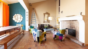 A living room with a wooden table, colorful chairs, a fireplace, and a ladder against the wall. - Villa 'L'acanthe' with Private Pool, Private Terrace, and Wi-Fi (Six-Fours-les-Plages)