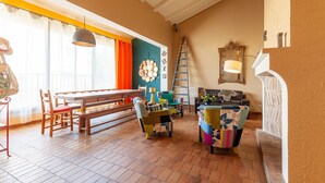 A spacious living area with a wooden bench, colorful chairs, a dining table, and a large window with curtains. - Villa 'L'acanthe' with Private Pool, Private Terrace, and Wi-Fi (Six-Fours-les-Plages)