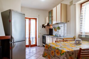 Una cocina con refrigerador, estufa, horno y una mesa cubierta con un mantel floral.