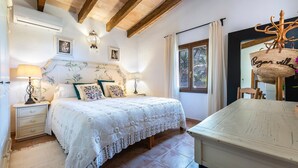 Une chambre à coucher avec un lit, des tables de chevet, une lampe, une suspension et une fenêtre.