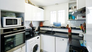 Una cocina moderna con electrodomésticos como microondas, horno y lavavajillas, y un ventanal que proporciona luz natural.