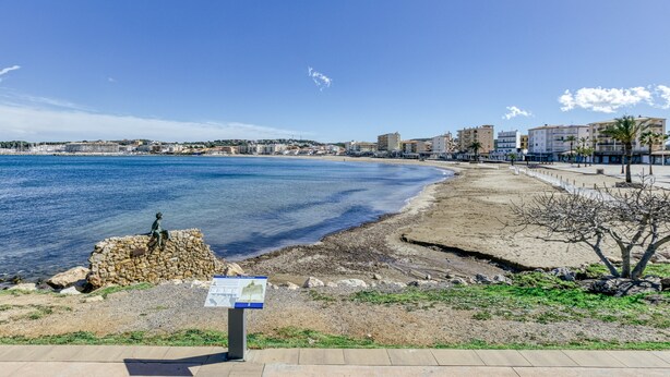 A coastal cityscape with a clear sky, a sandy beach, and a stone monument. - Apartment 'Escala Riells' with Balcony and Wi-Fi (Escala)