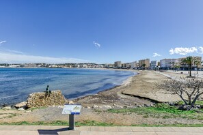 Un paysage urbain côtier, avec un ciel dégagé, une plage de sable et un monument en pierre.