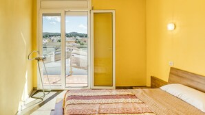 A room with a bed, a window with a view of buildings, and a door leading to an outdoor area. - Apartment 'Escala Riells' with Balcony and Wi-Fi (Escala)