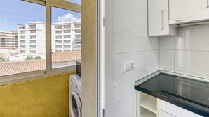 A kitchen with a window, a washing machine, and white cabinets. - Apartment 'Escala Riells' with Balcony and Wi-Fi (Escala)