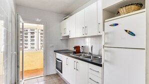 A modern kitchen with white cabinets, a stainless steel sink, and a refrigerator with magnets. - Apartment 'Escala Riells' with Balcony and Wi-Fi (Escala)