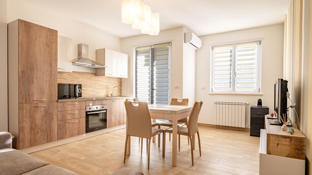 Una cocina moderna con armarios de madera, una mesa de comedor con sillas y un horno empotrado.
