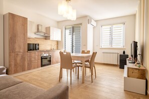 A modern kitchen with wooden cabinets, a dining table with chairs, and a built-in oven.